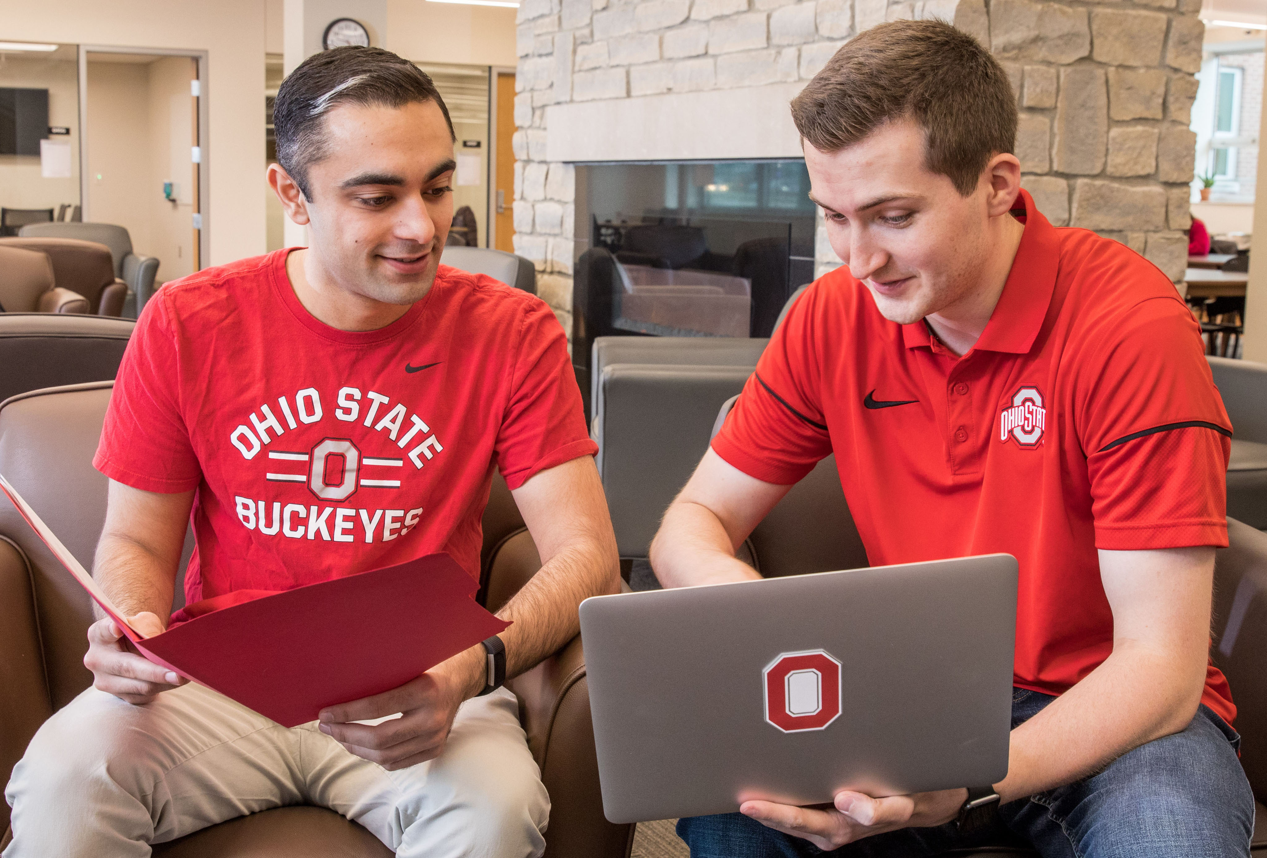 Two Buckeyes talking to each other about coding. One is pointing to the screen of a laptop.