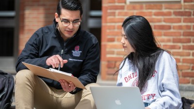 Two online MBA program students students have a conversation outside the classroom.