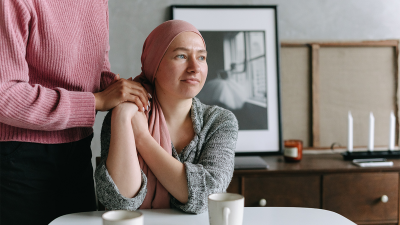 Palliative care specialist cares for woman patient with a pink head scarf