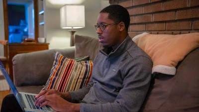 A man using a laptop while sitting on a couch at home