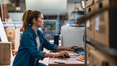 A young woman works at a computer to earn her online supply chain management master's degree.