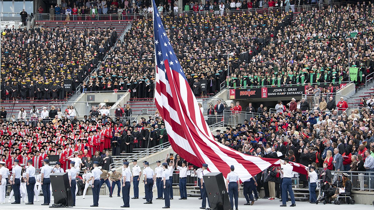 Students raise the American flag during a commencement ceremony,.