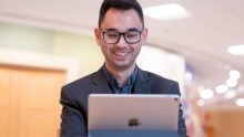 Smiling man looking at an iPad and participating in synchronous online learning.