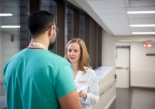 A nurse practitioner consults with a doctor in the halls of a hospital.