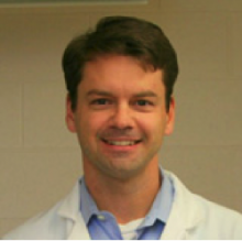 Online Master's in Pharmacology instructor Dr. Mitch A. Phelps smiles in a lab coat.