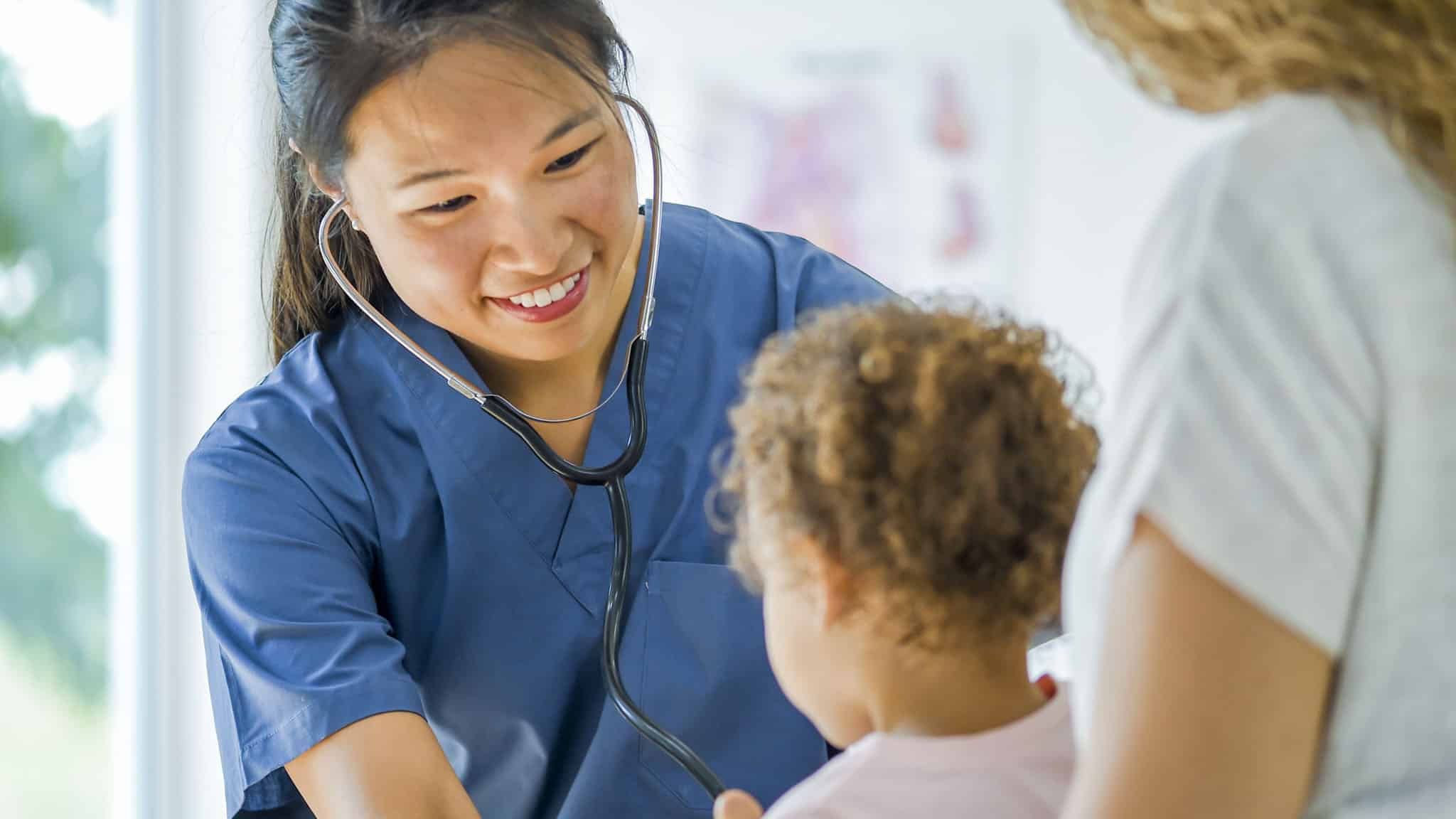 Nurse practitioner with a stethoscope cares for young patient