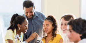 A teacher oversees a science experiment performed by a group of students