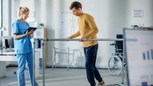 Rehabilitation specialist oversees patient working in physical therapy session.