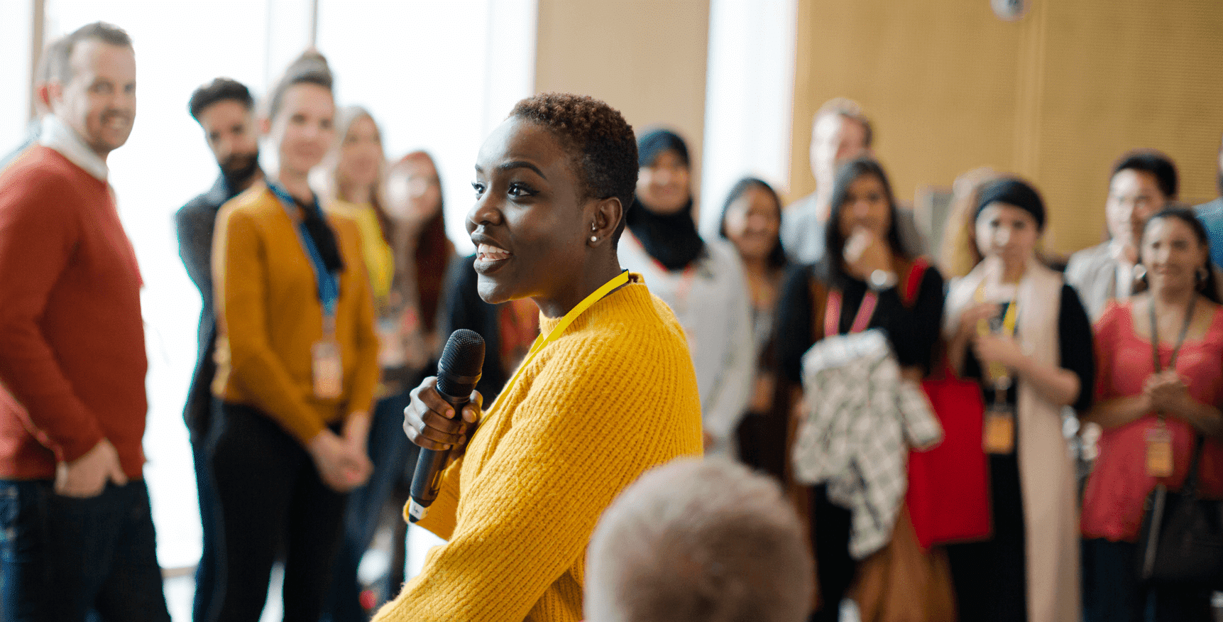 A women smiles holding a microphone as she speaks to a group
