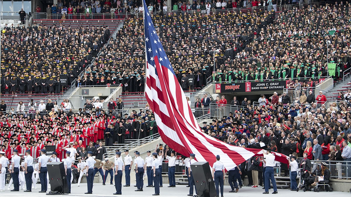 Students raise the American flag during a commencement ceremony.