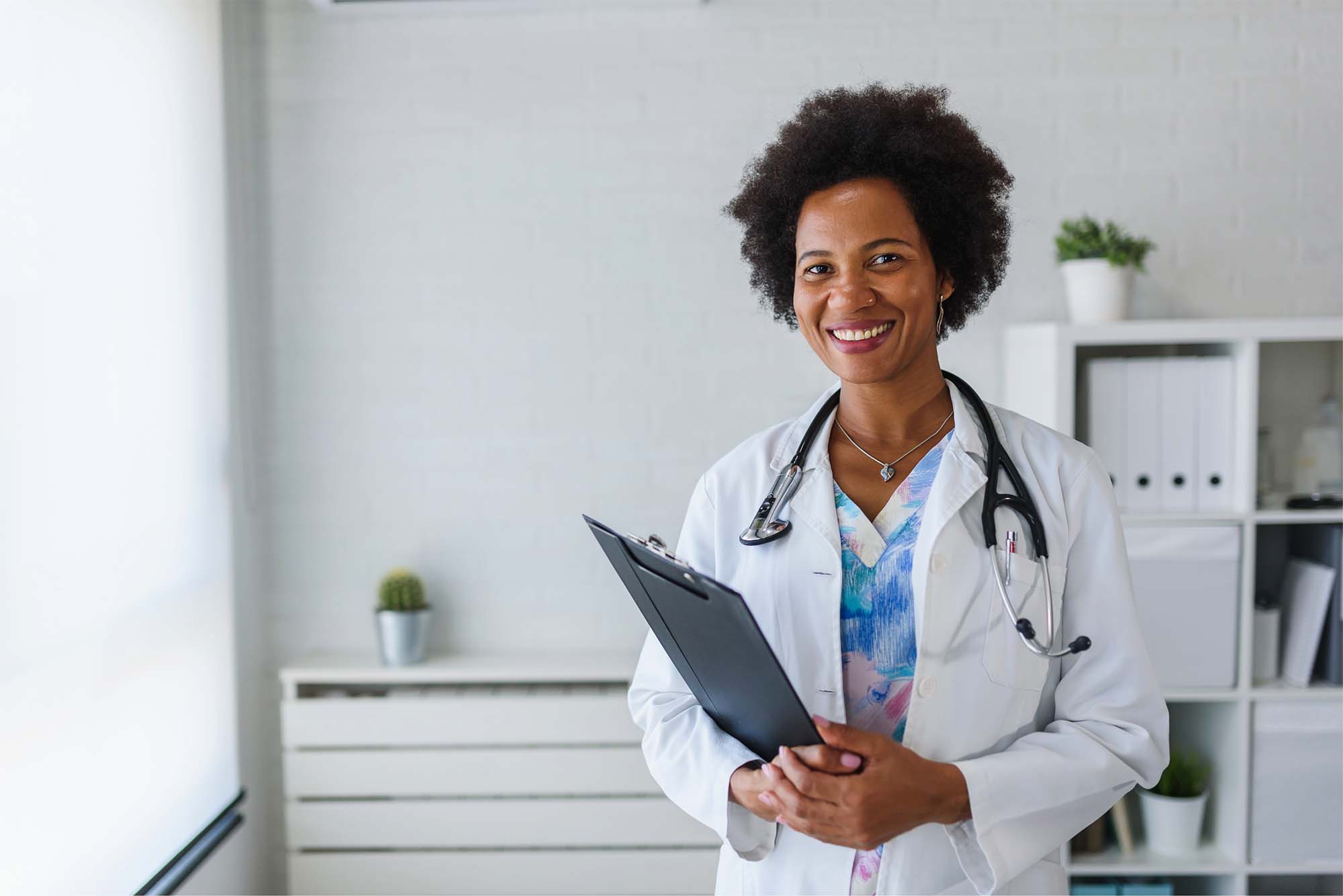 Female woman with her DNP degree stands proudly in a white coat.