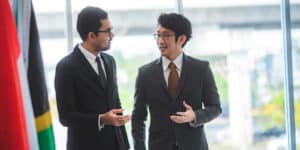 Two men talking to each other walking down a hallway