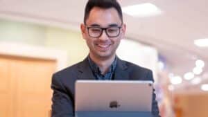 A smiling man looks at an iPad.