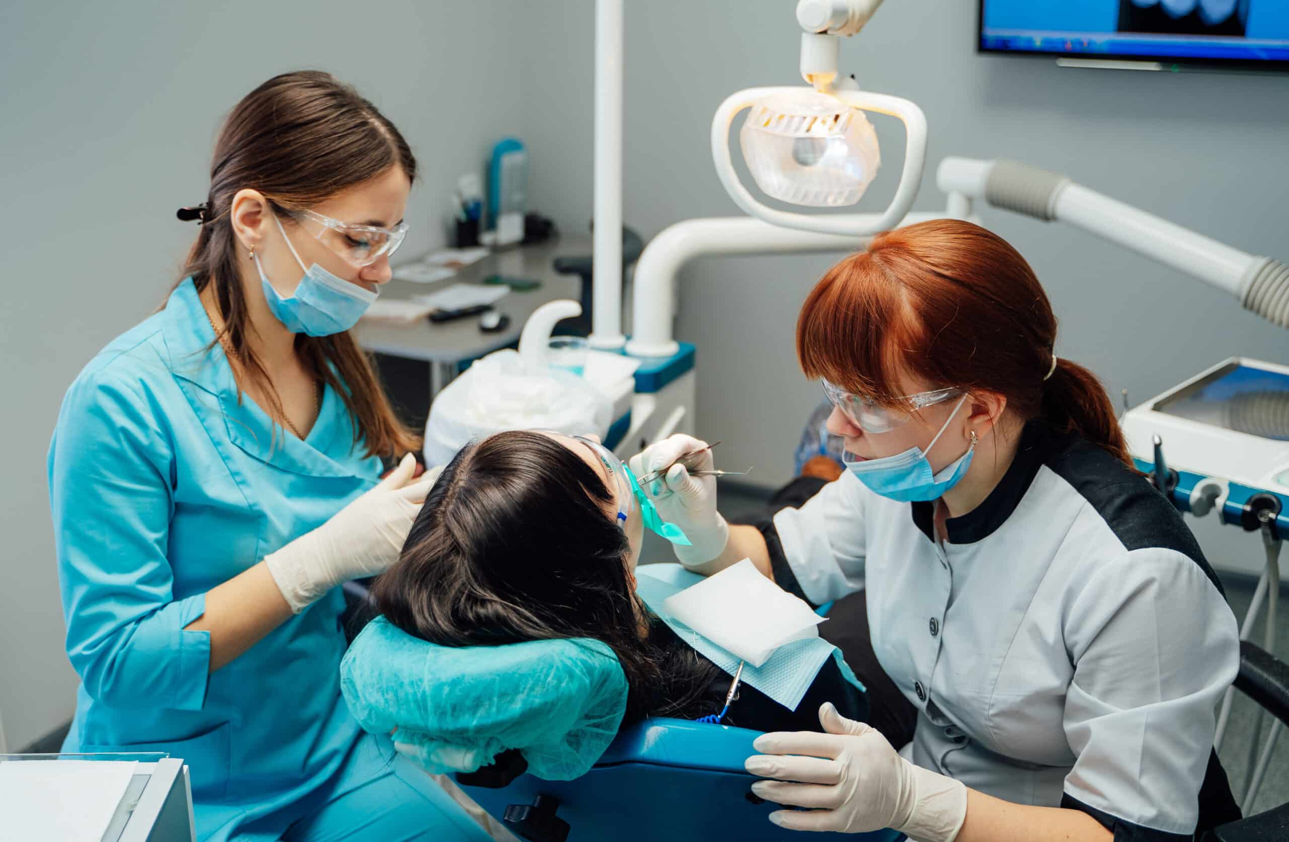 Dental hygienist helping dentist with patient.
