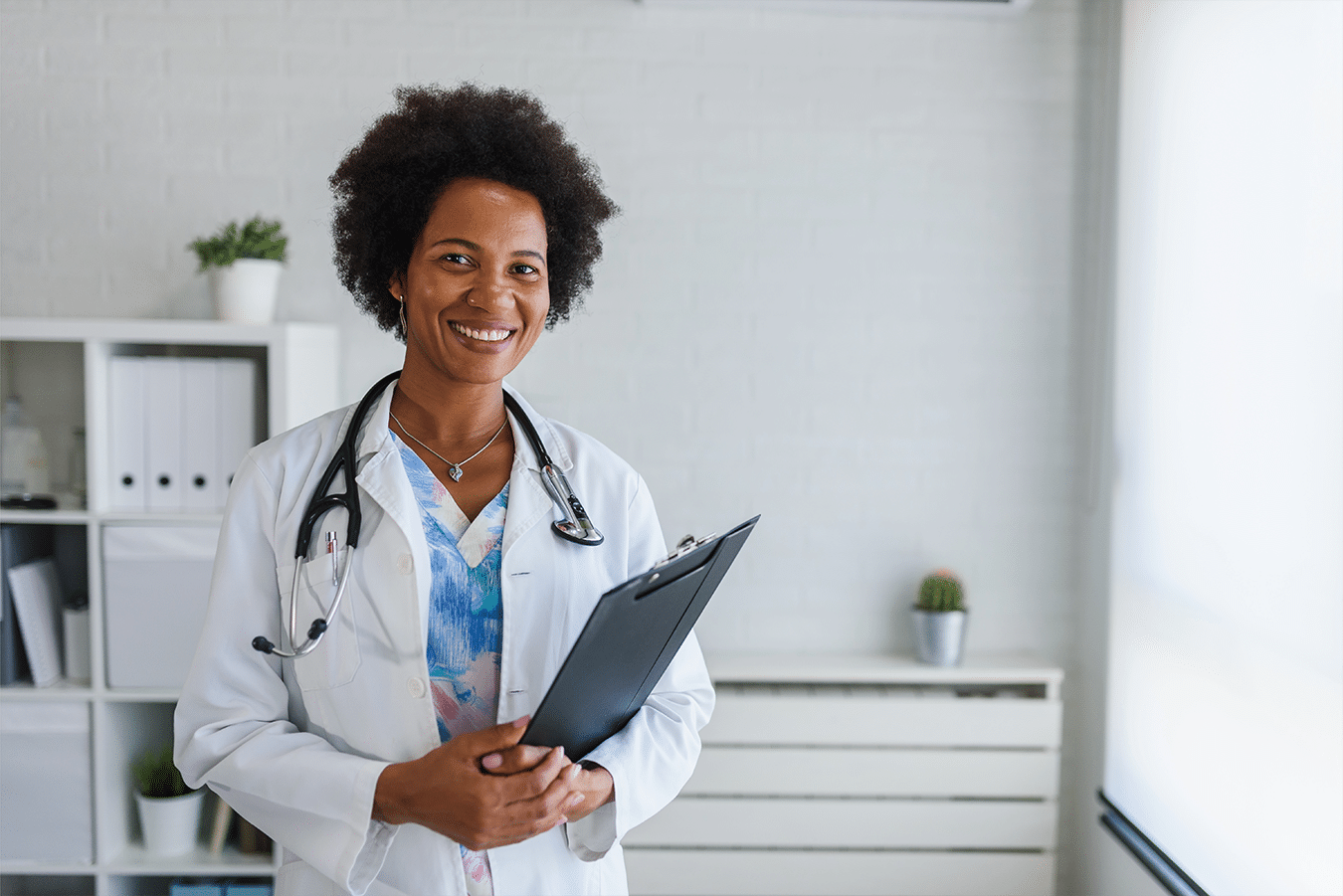 Female woman with her DNP degree stands proudly in a white coat.