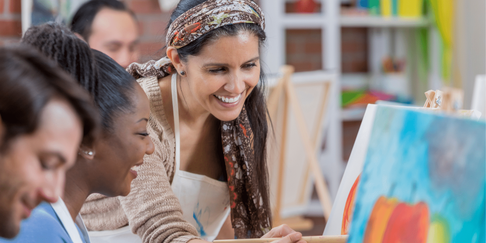 An art teacher paints a canvas with a group of students