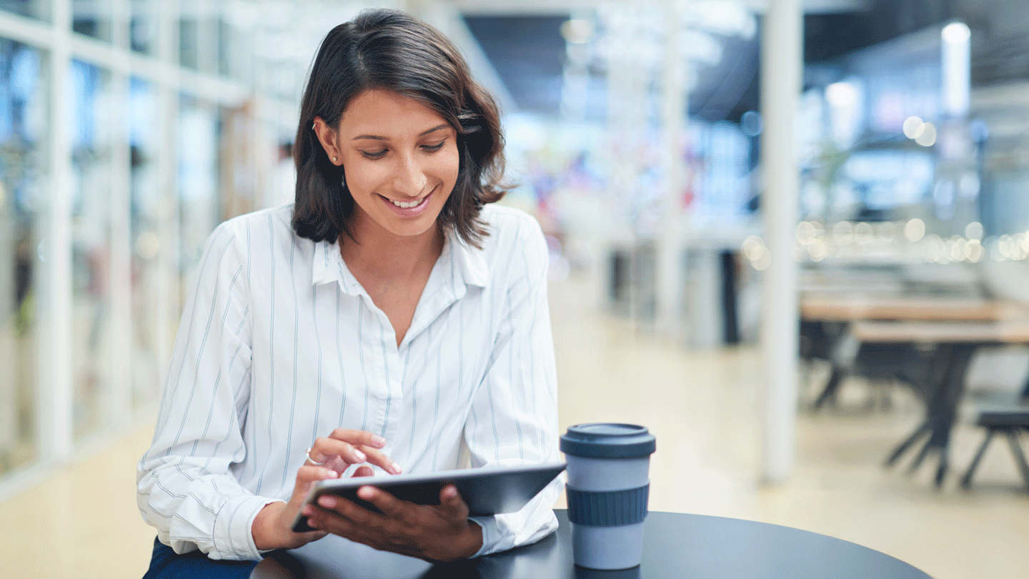 Female working professional using a tablet at a coffee shop.