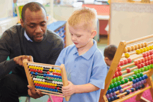 Board Certified Behavior Analyst working with a child using a counting tool in a classroom setting