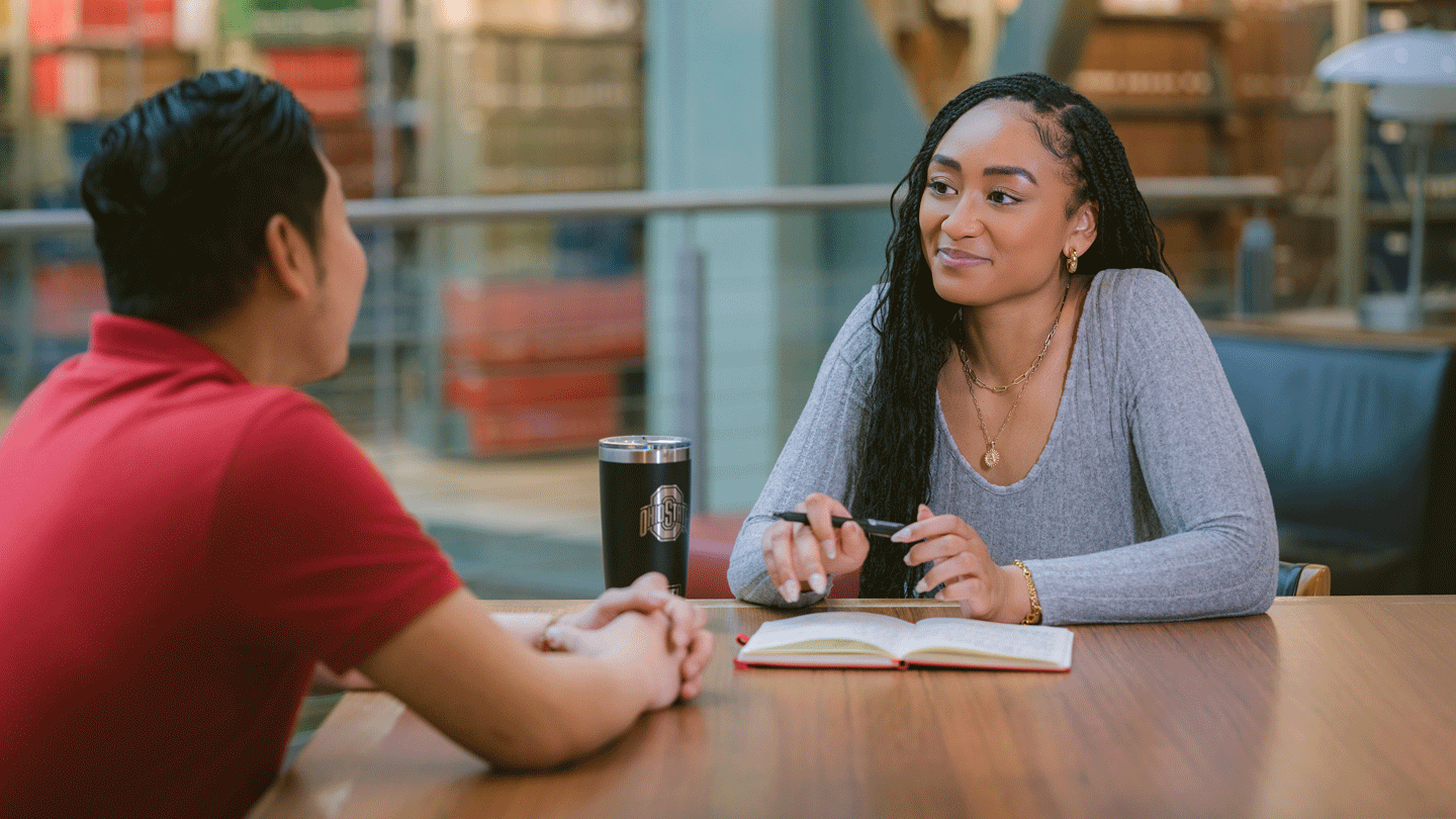 Two professional adults having a conversation in a library.