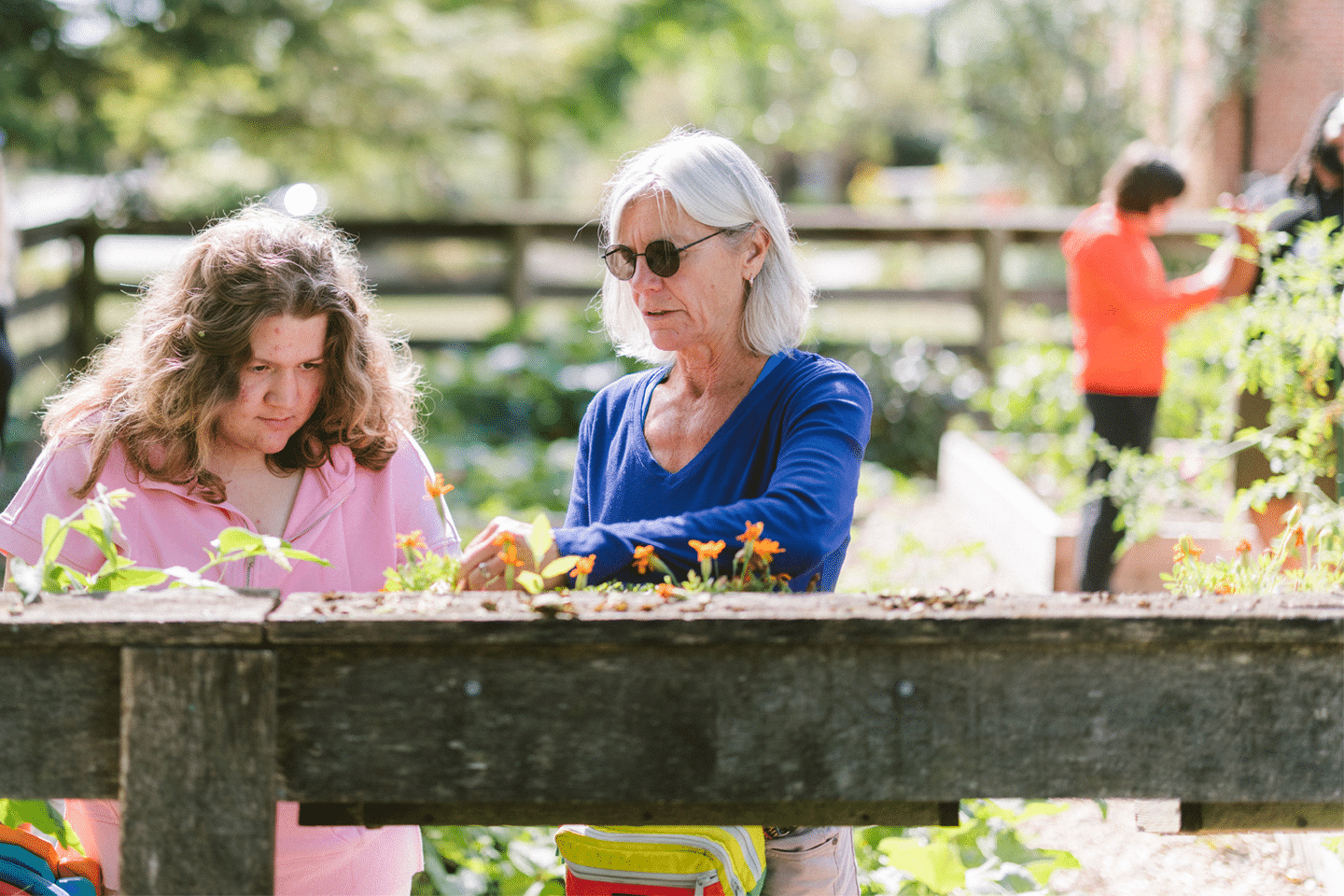 Applied behavior analysis professional supports client during an outdoor gardening activity.