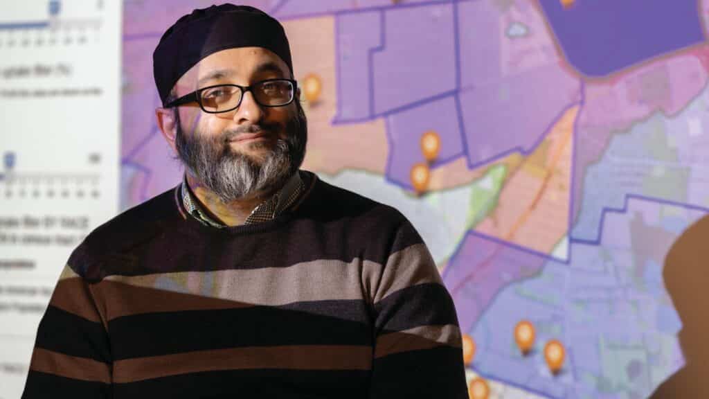 Dr. Hader stands in front of a map projection.