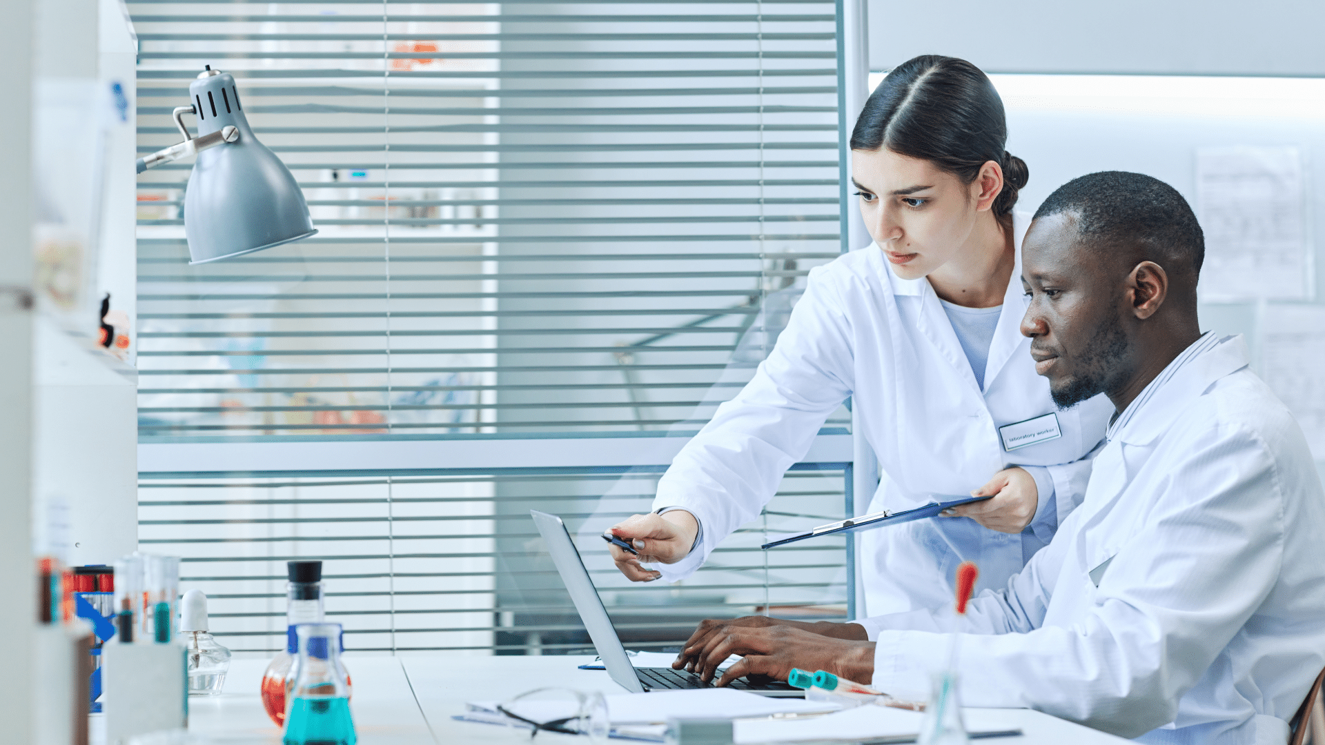Two scientists working together, looking at a laptop