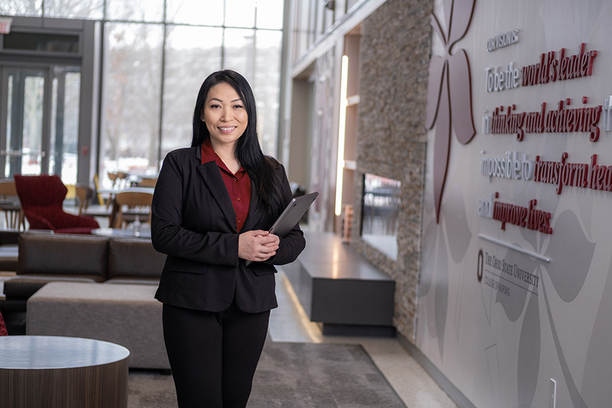 An Ohio State Executive Master of Health Administration graduate holding a laptop