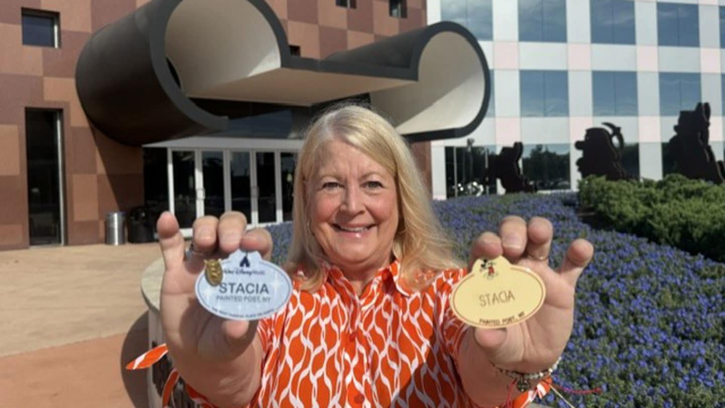 Stacia holding up her work badges on her last day of work before retirement.